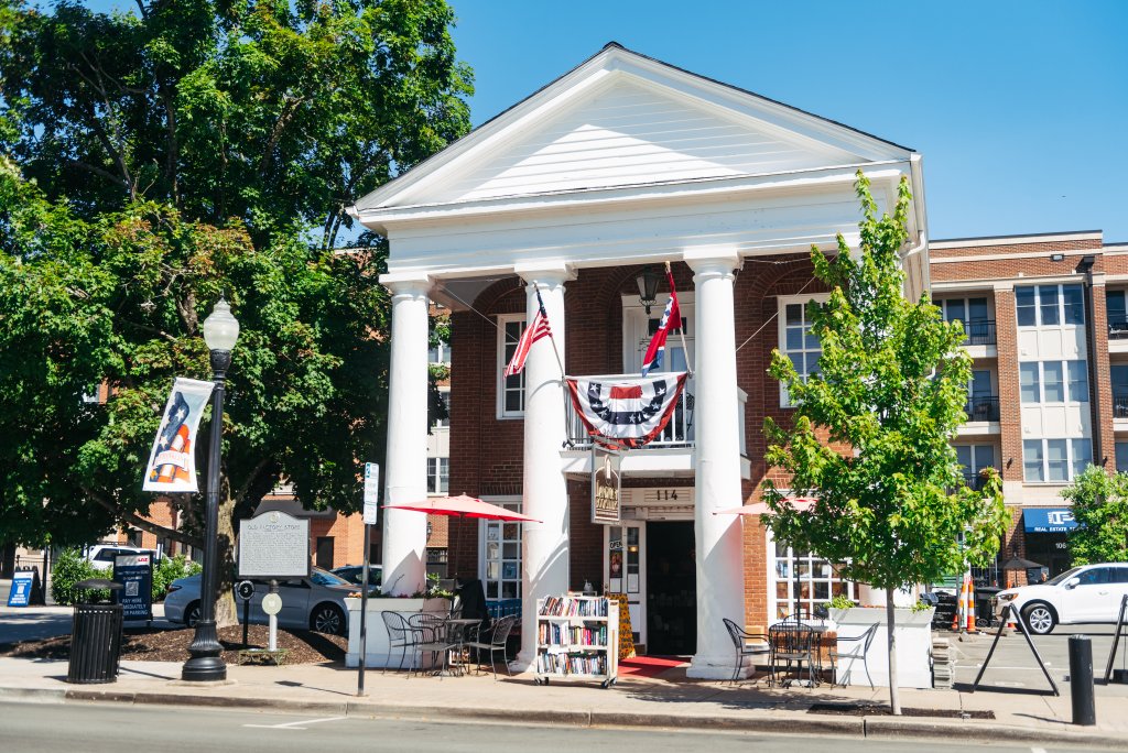 A charming brick building with white columns and American flags, surrounded by trees and outdoor seating in Williamson County, Tennessee.