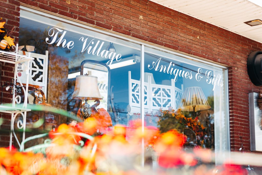 A charming antique shop with a vibrant window display featuring autumnal flowers and elegant vintage items in Williamson County, Tennessee.