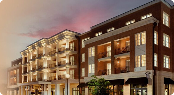 A modern apartment complex with illuminated balconies and large windows at dusk in Williamson County, Tennessee.
