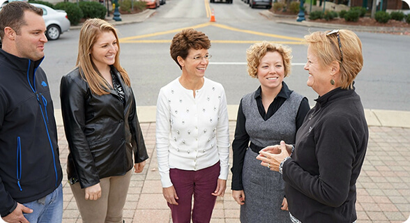 Five women are standing and smiling on a brick sidewalk in a town square in Williamson County, Tennessee.
