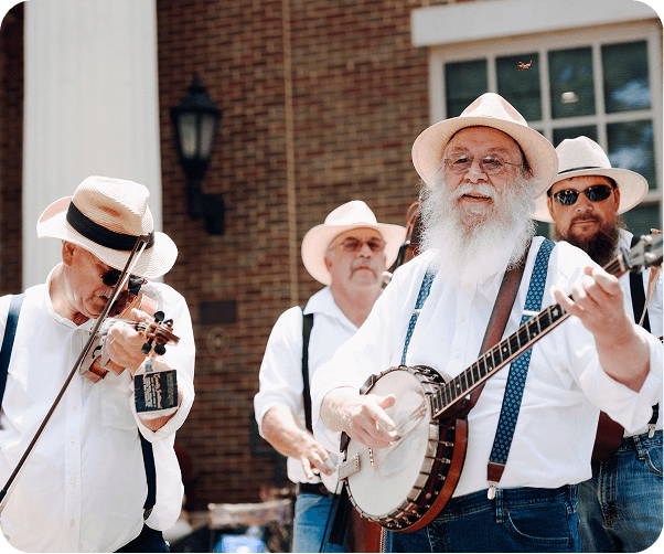 Bluegrass Along the Harpeth Four elderly musicians in white suits and hats play bluegrass music on a porch in Williamson County, Tennessee.