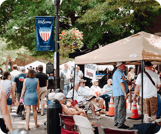 Bluegrass Along the Harpeth A lively street fair with vendors, musicians, and a crowd enjoying the sunny day in Williamson County, Tennessee.