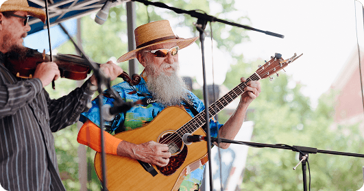 Bluegrass Along the Harpeth Two musicians, one playing violin and the other guitar, perform outdoors under a canopy in Williamson County, Tennessee.