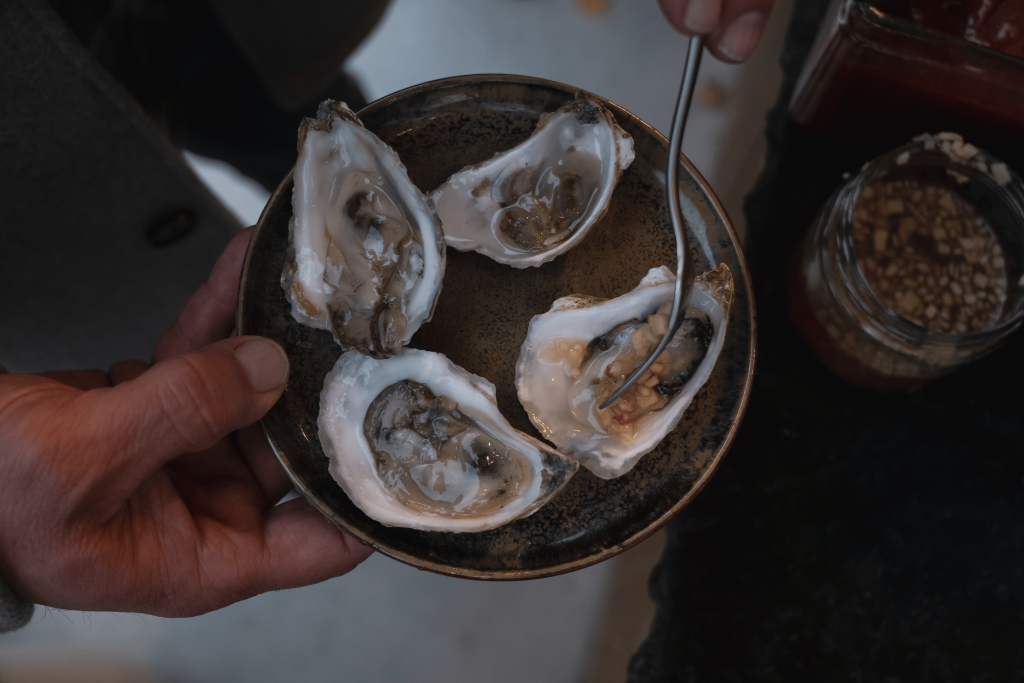 Events A person holds a plate of four fresh oysters on the half shell, ready to be enjoyed in Williamson County, Tennessee.