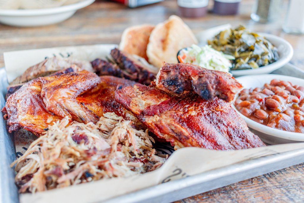 A mouthwatering barbecue platter featuring smoked ribs, chicken wings, pulled pork, baked beans, collard greens, and cornbread in Williamson County, Tennessee.