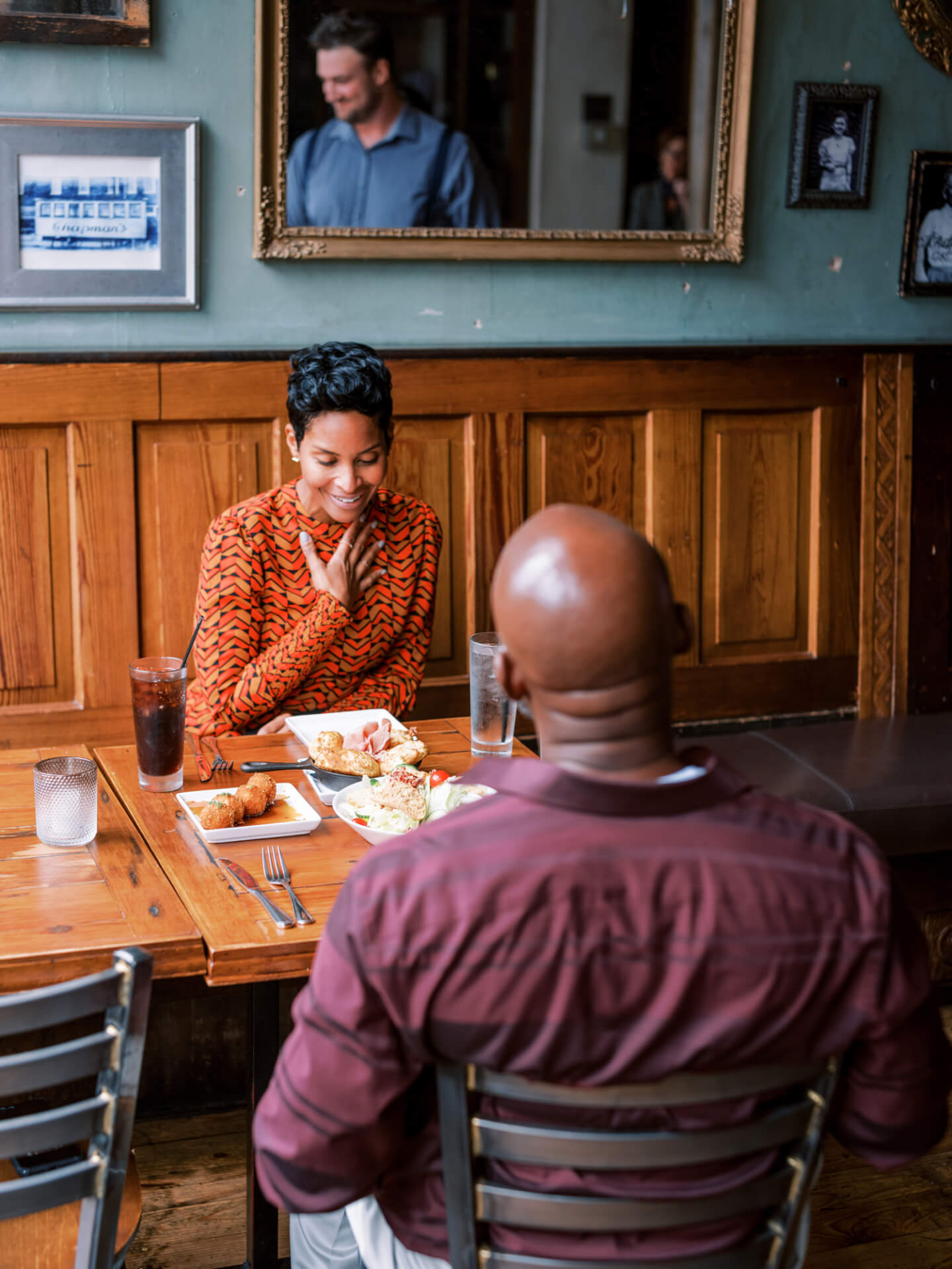 A couple enjoys a meal together at a cozy restaurant with wooden paneling and framed pictures on the walls in Williamson County, Tennessee.