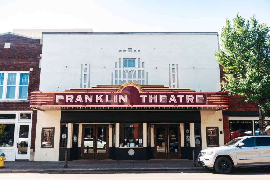 The Franklin Theatre, a historic movie theater with a distinctive Art Deco marquee, stands prominently on a street corner in Williamson County, Tennessee.