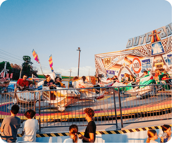 A vibrant amusement park ride with colorful cars spinning around a central axis, filled with excited riders and onlookers in Williamson County, Tennessee.