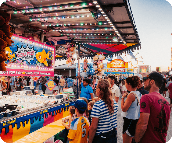 A bustling carnival midway filled with colorful rides, games, and food stalls attracting crowds of people in Williamson County, Tennessee.