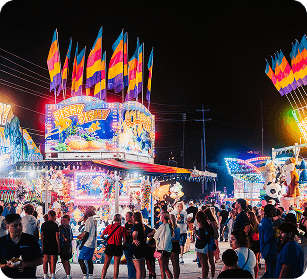 A vibrant night scene at a bustling county fair with colorful rides, games, and crowds of people enjoying the festivities in Williamson County, Tennessee.