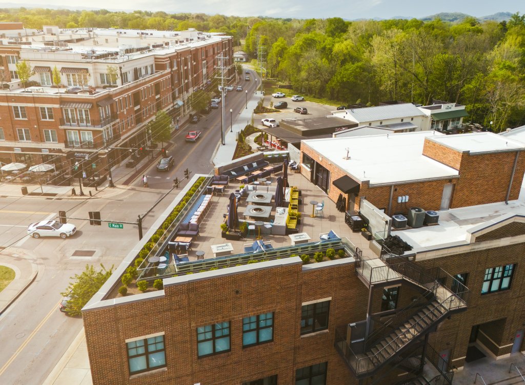 The 8 Best Late-Night Spots for Live Music, Cocktails & More in Franklin A bustling urban scene with a mix of modern and historic buildings, a rooftop garden, and a busy street filled with cars and pedestrians in Williamson County, Tennessee.