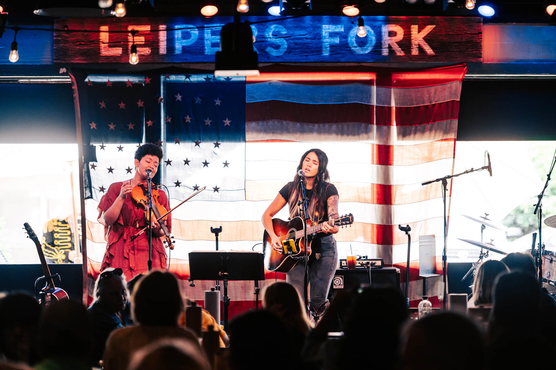 Top 10 Things to Do in Franklin Two women perform music on stage in front of an American flag in Williamson County, Tennessee.