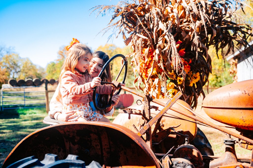 A young girl and her mother sitting on an old tractor at a farm in Williamson County, Tennessee.
