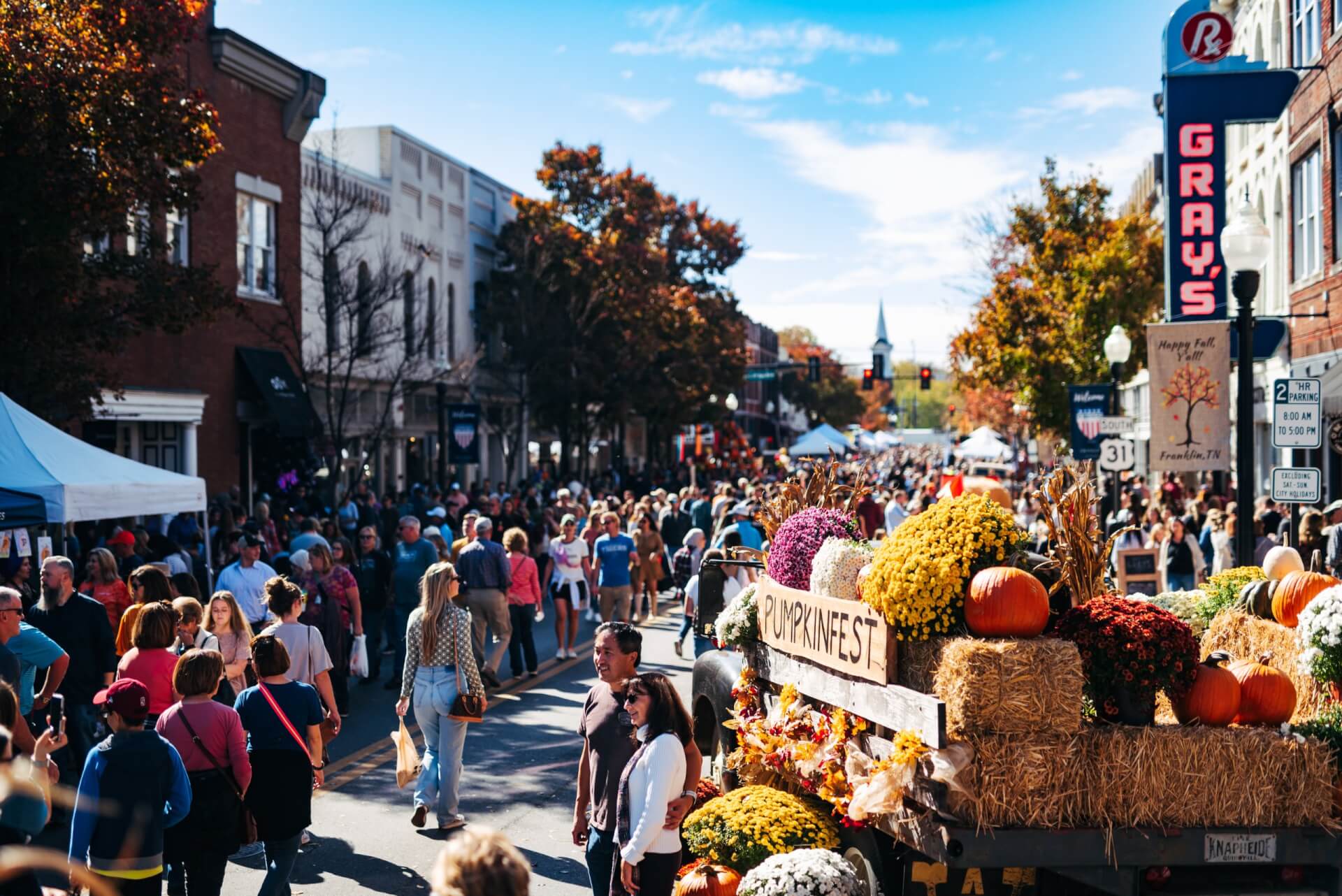 PumpkinFest A crowded street festival with autumn decorations, pumpkins, and hay bales on a sunny day in Williamson County, Tennessee.