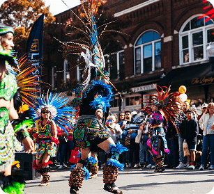 PumpkinFest Performers in vibrant, feathered traditional costumes dance in a street parade in Williamson County, Tennessee.
