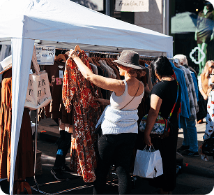 PumpkinFest Two women browsing clothing at an outdoor market stall under a white canopy in Williamson County, Tennessee.