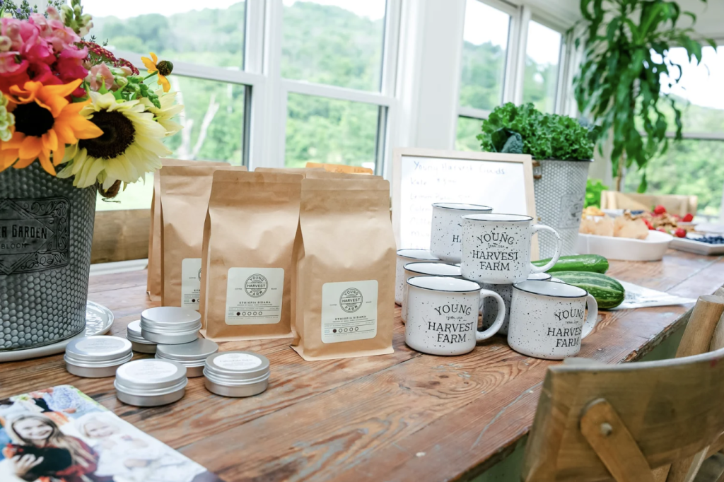 Events A wooden table displays coffee bags, branded mugs, small tins, and fresh produce in Williamson County, Tennessee.