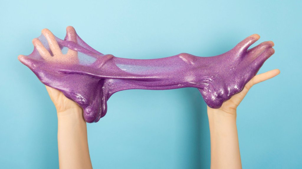 Events Hands stretching a piece of glittery purple slime against a light blue background in Williamson County, Tennessee.