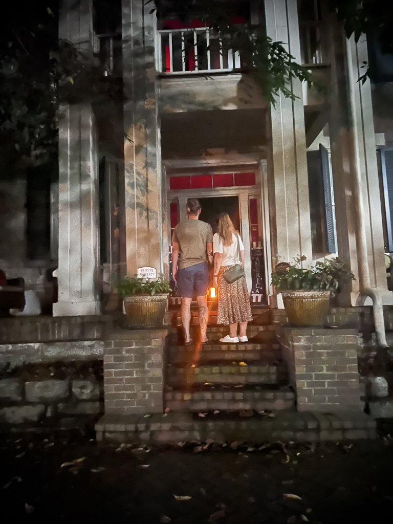 A couple stands on the front porch of a house at night in Williamson County, Tennessee.