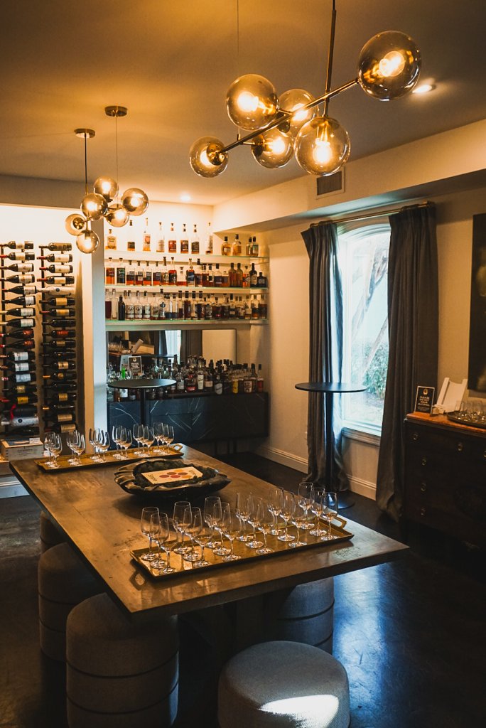 Shaken, Stirred & Seriously Good: The Martini Class A tasting room with a large wooden table, wine glasses, and shelves of liquor bottles in Williamson County, Tennessee.