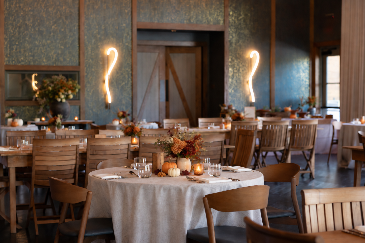 A dining room decorated for autumn with pumpkins and floral centerpieces on round tables in Williamson County, Tennessee.