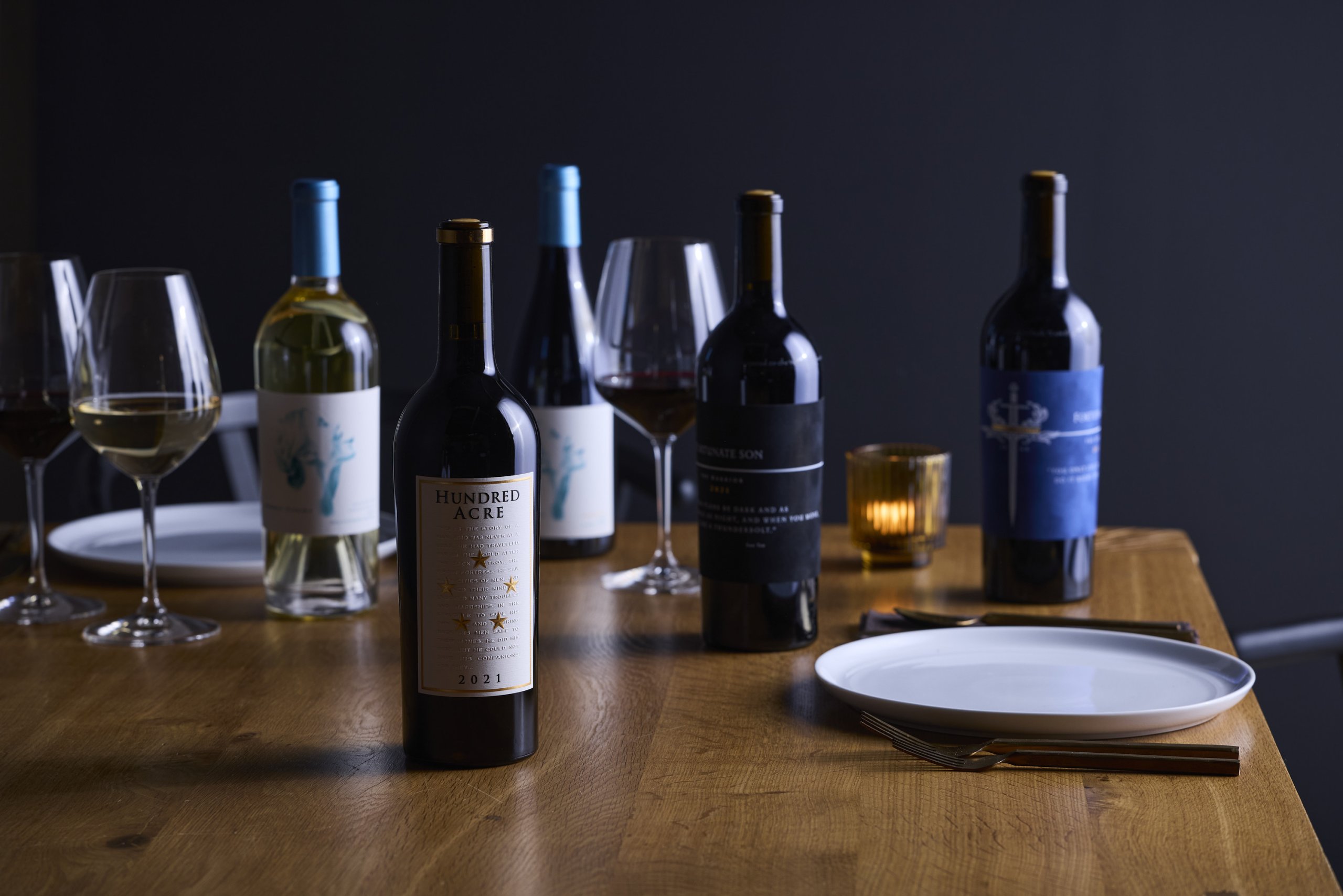Several wine bottles and glasses arranged on a wooden dining table in Williamson County, Tennessee.
