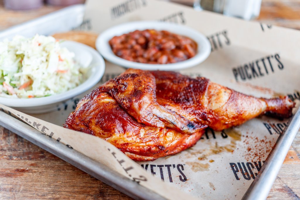 A roasted chicken quarter served with coleslaw and baked beans on a tray in Williamson County, Tennessee.