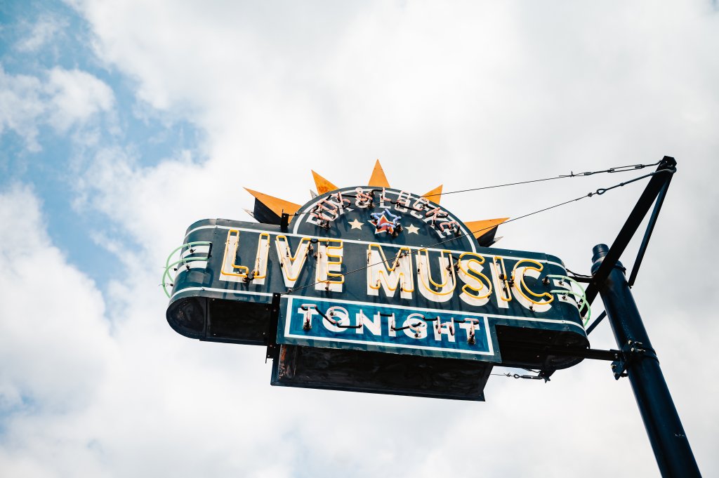 Discover the Surprisingly Unique Music History of Franklin, Tennessee A vintage-style neon sign advertising live music against a cloudy sky in Williamson County, Tennessee.