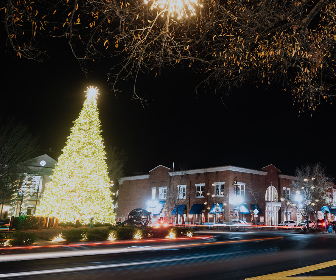 A Hallmark Christmas Escape A brightly lit Christmas tree stands in a town square at night in Williamson County, Tennessee.