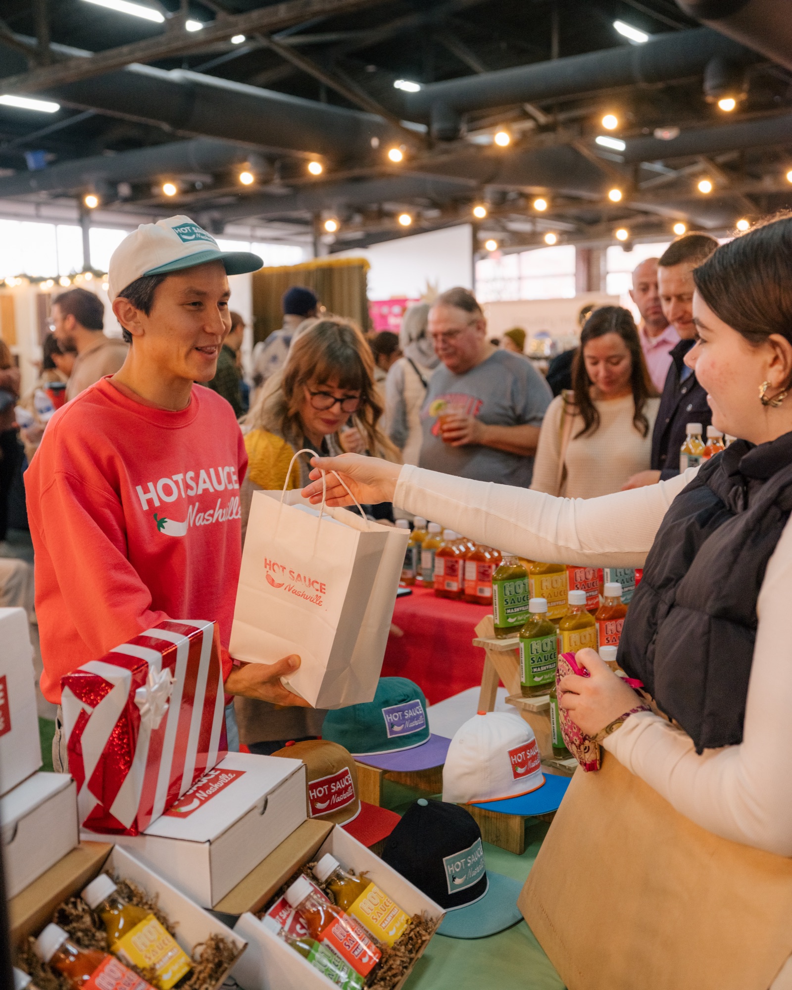 Made Market A vendor in a red sweatshirt hands a shopping bag to a customer in Williamson County, Tennessee.