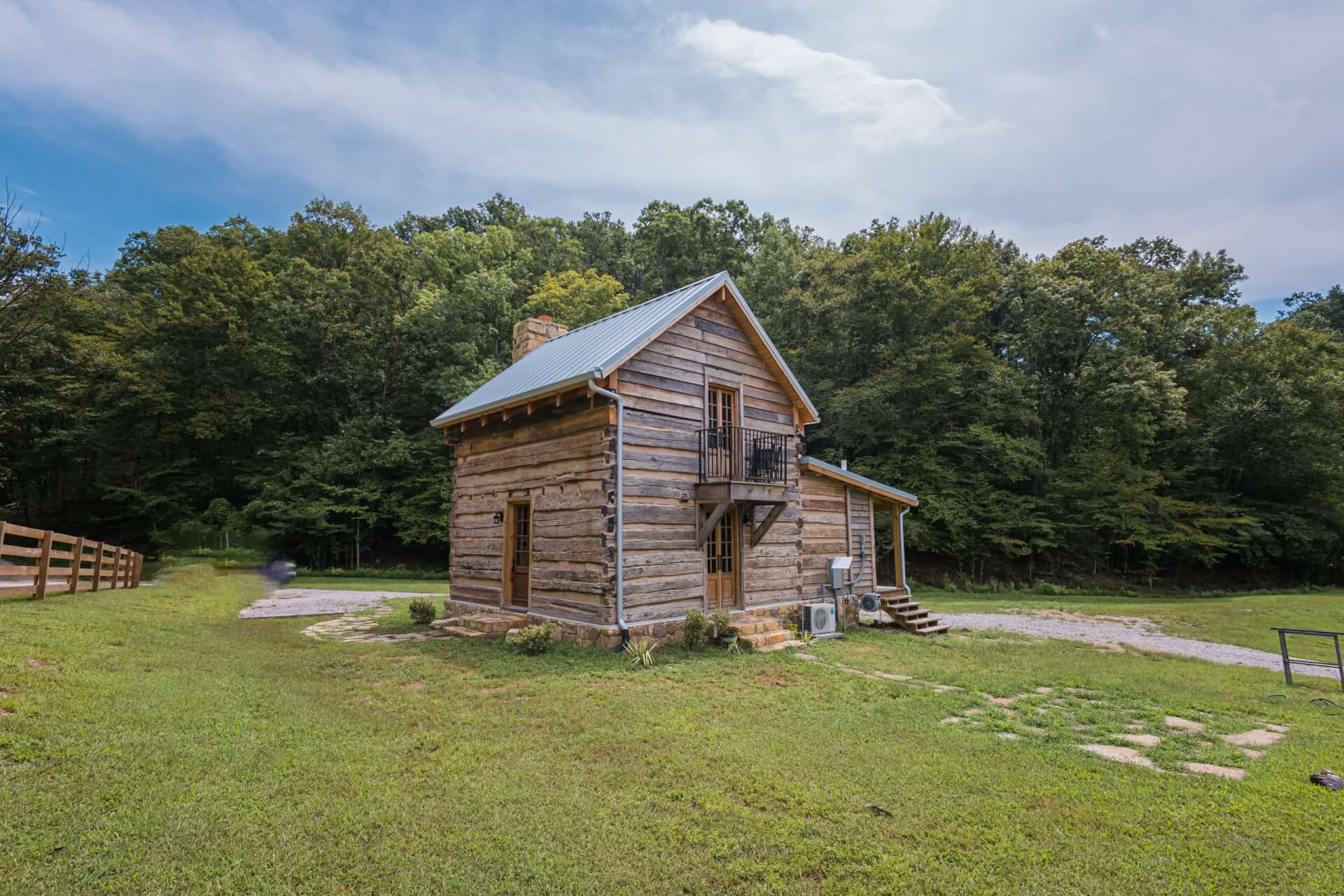 Promise Land Airbnb A rustic two-story log cabin sits in a grassy clearing near a forest in Williamson County, Tennessee.