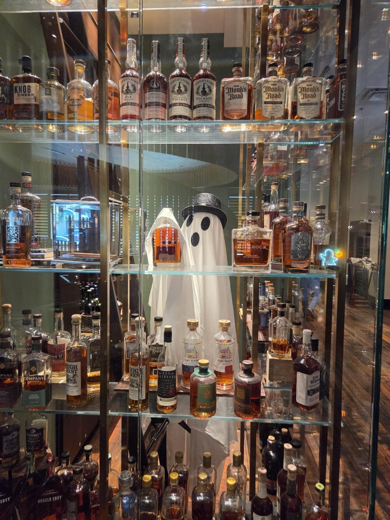 A ghost costume wearing a top hat stands among shelves of whiskey bottles in Williamson County, Tennessee.