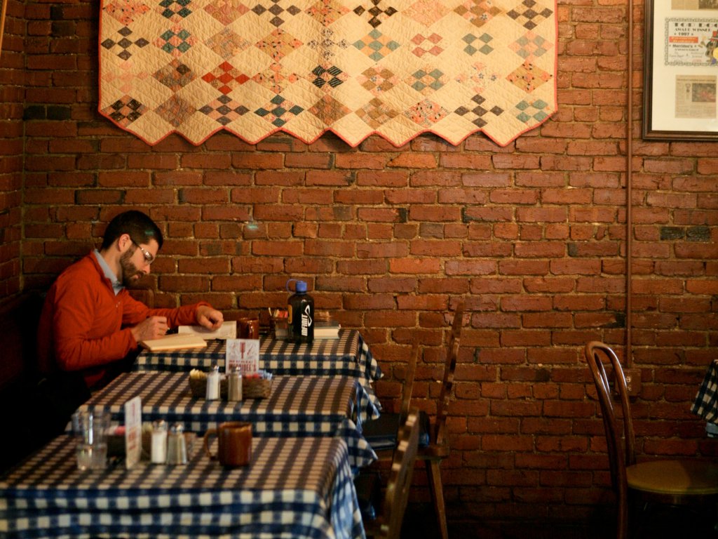 A Family Recipe, a Famous Bakery, and a Franklin Story: The Makings of Merridee's Breadbasket A man in a red sweater reads a book at a cafe table in Williamson County, Tennessee.