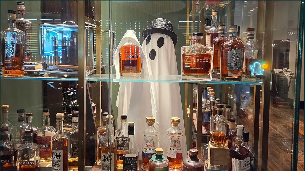 A ghost decoration wearing a top hat stands among bottles of whiskey on shelves in Williamson County, Tennessee.