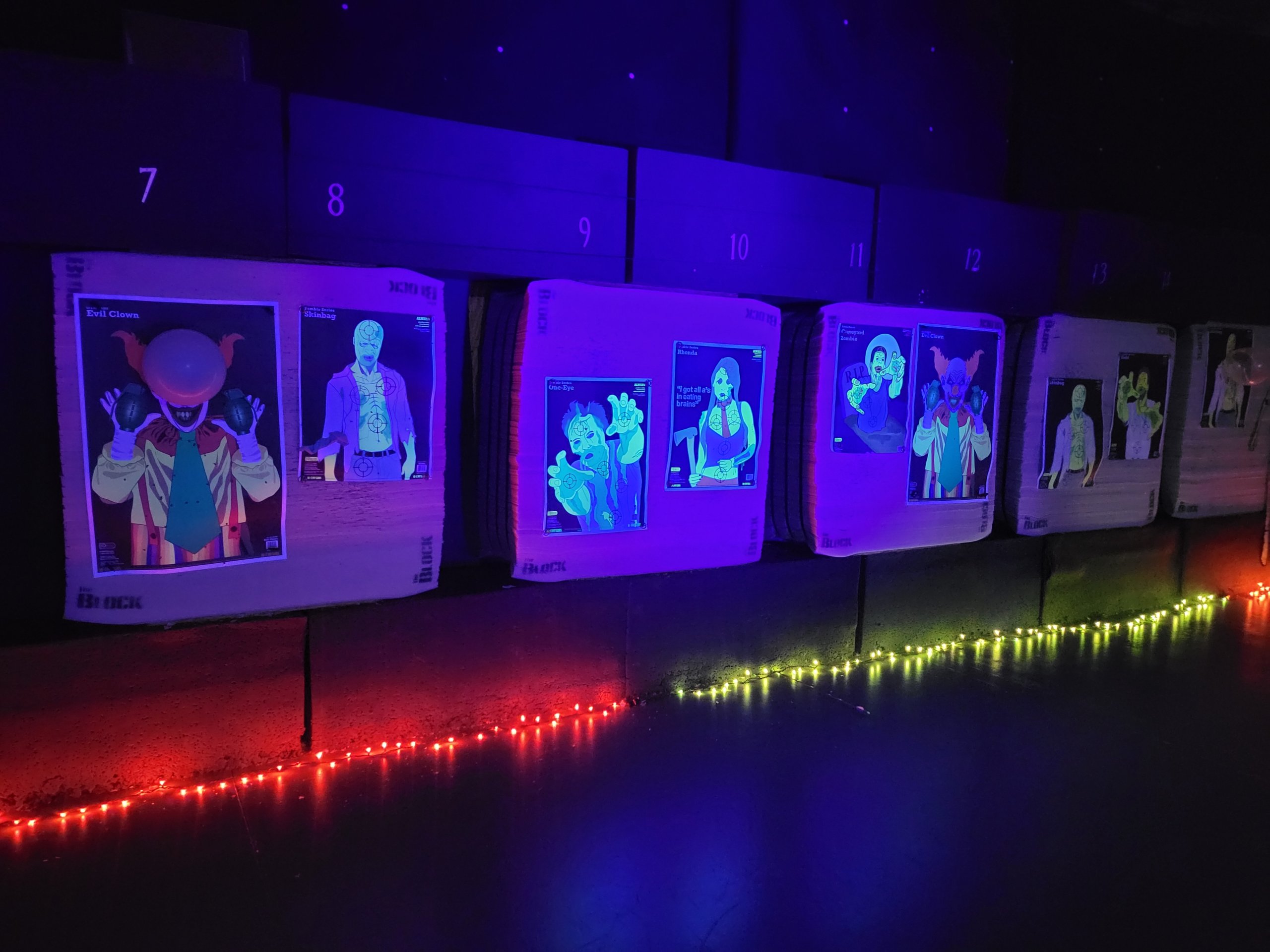 Haunted Archery Range Fluorescent zombie and clown targets displayed on archery blocks in a dark room in Williamson County, Tennessee.