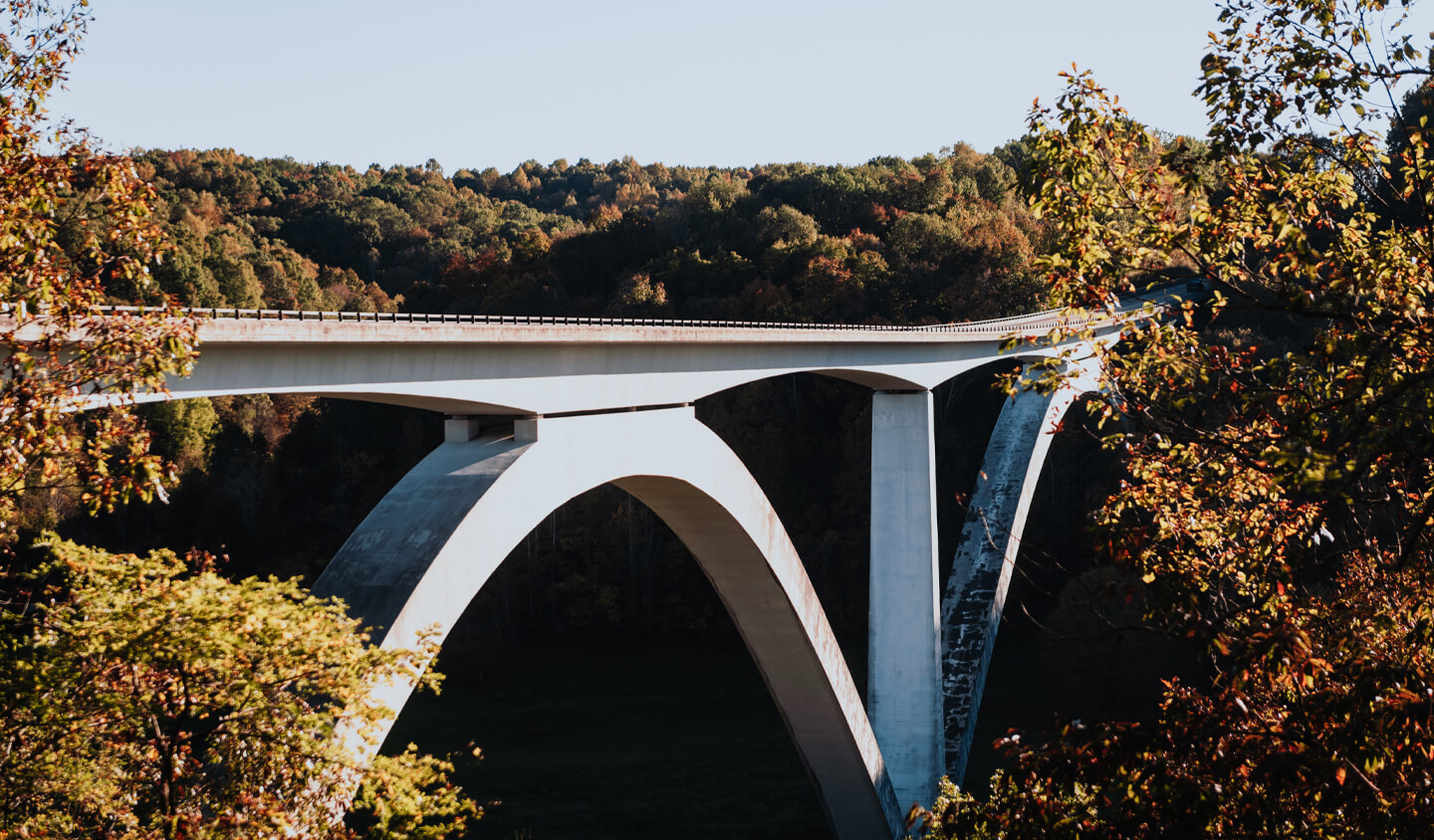 Homepage A large concrete arch bridge spans a valley surrounded by autumn trees in Williamson County, Tennessee.