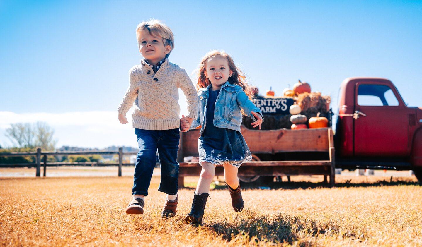 Homepage A young boy and girl holding hands while running through a field in Williamson County, Tennessee.