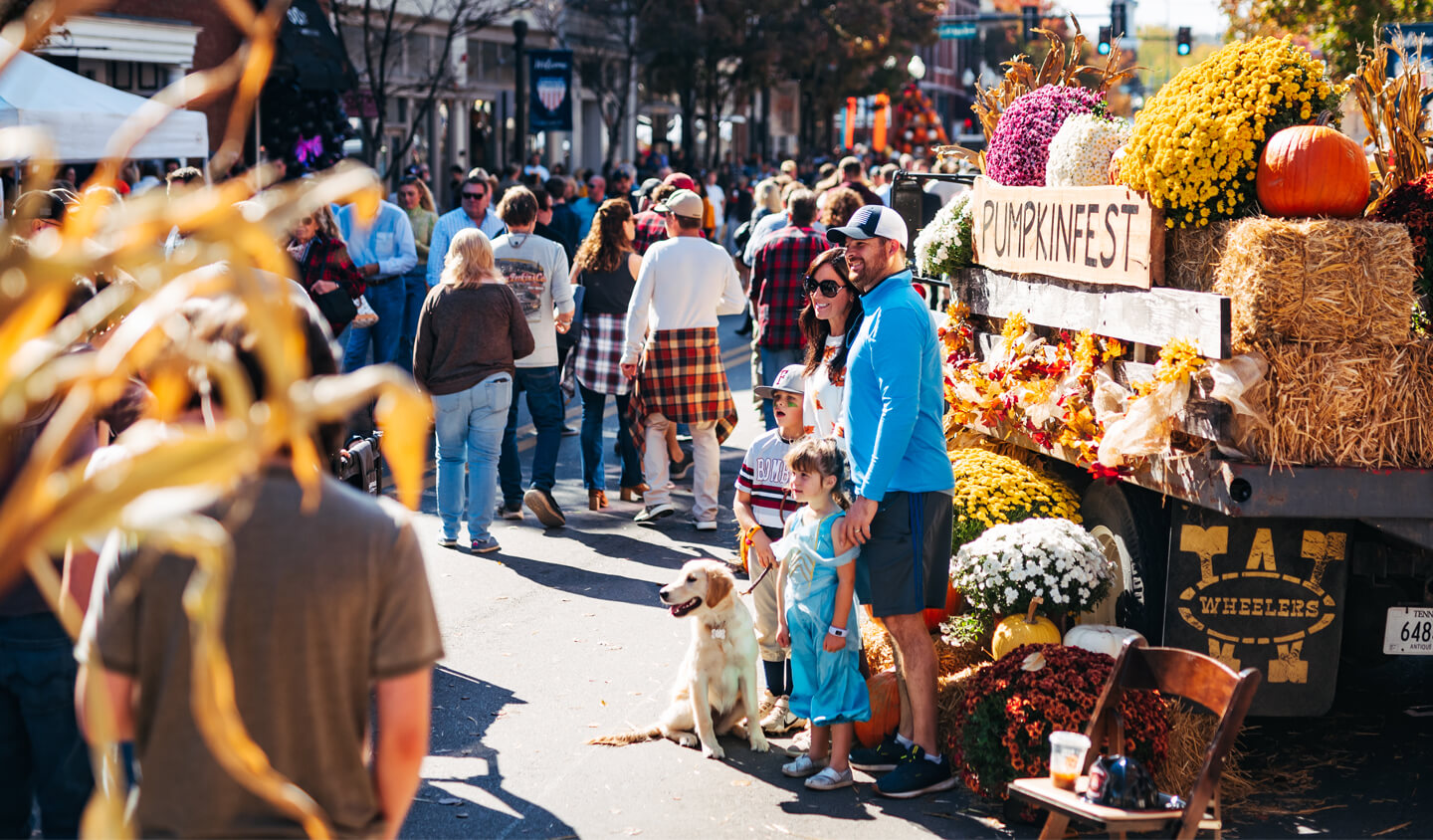 Homepage A family poses for a photo with their dog at a festive pumpkin street fair in Williamson County, Tennessee.