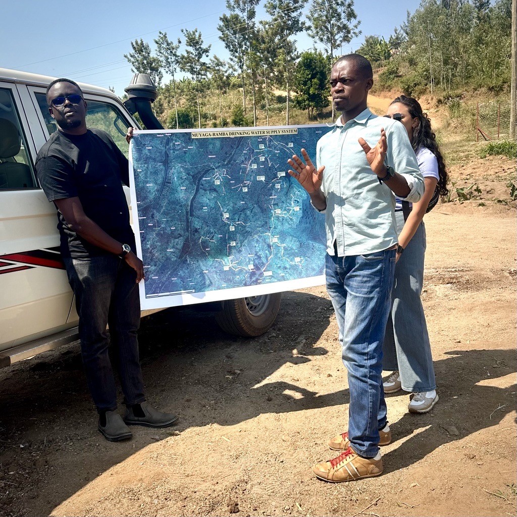 Water For People team members in Rwanda showing a map of a recently-completed water system in Nyamagabe District. 