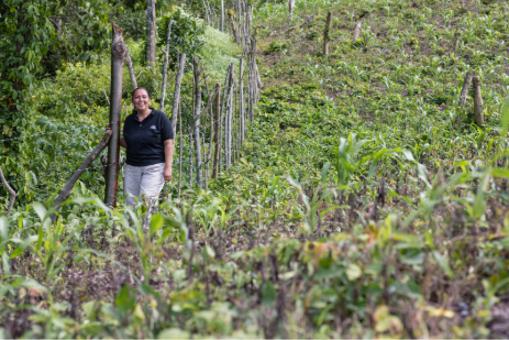 Carmen walks along a narrow, steep hillside path surrounded by young trees and dense green vegetation in La Tigra, Honduras, highlighting reforestation efforts that protect local water sources.