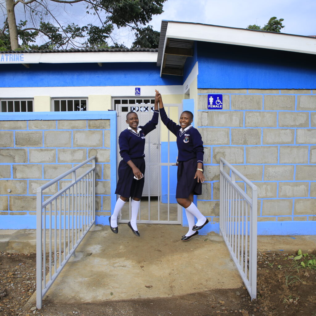 Students high five in front of their new bathroom facilities