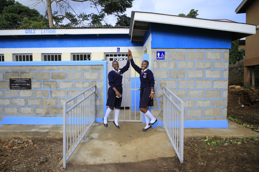 Students high five in front of their new bathroom facilities