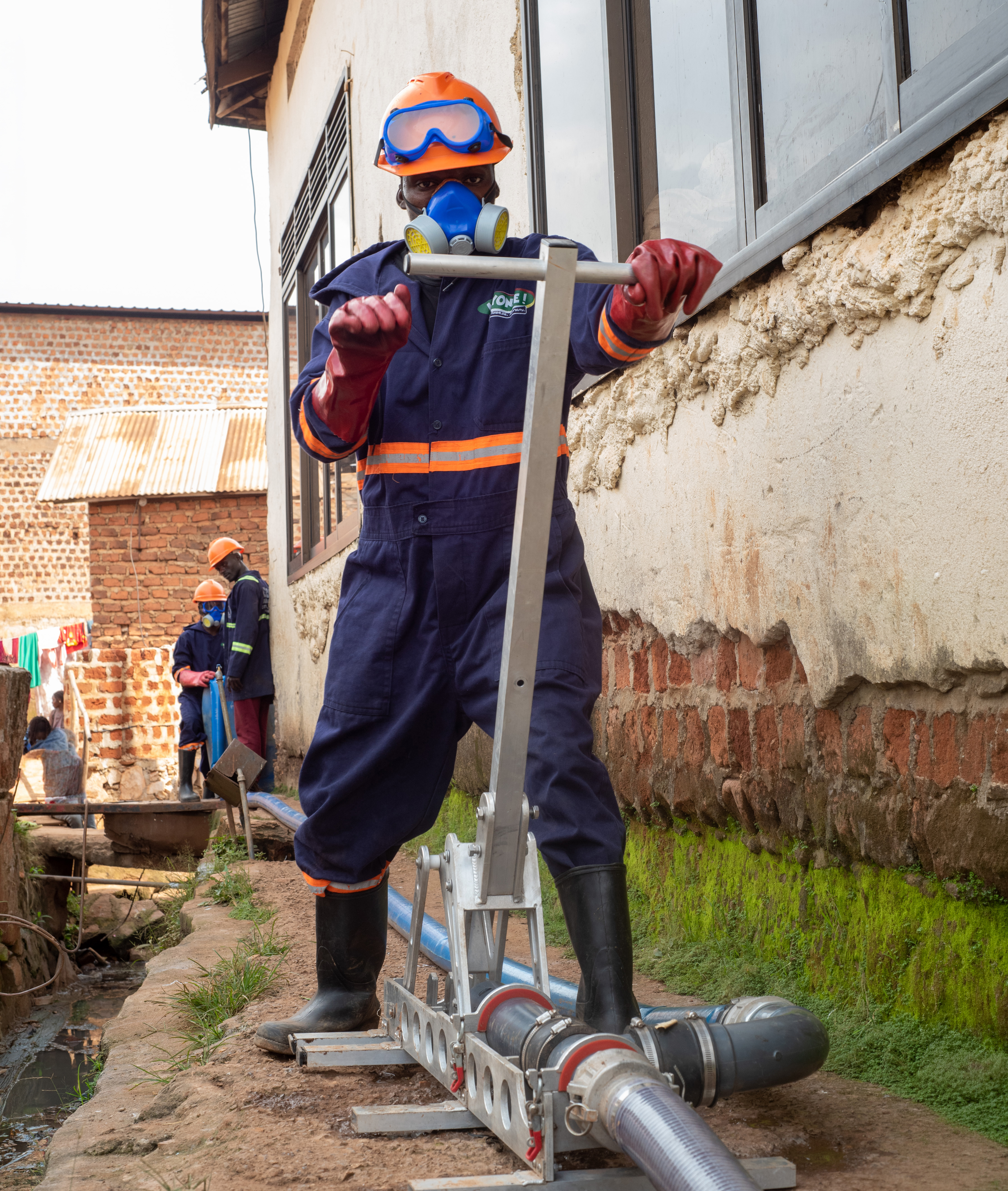 A pit emptier uses the Gulper, a pit-emptying pump, while dressed in safety gear.
